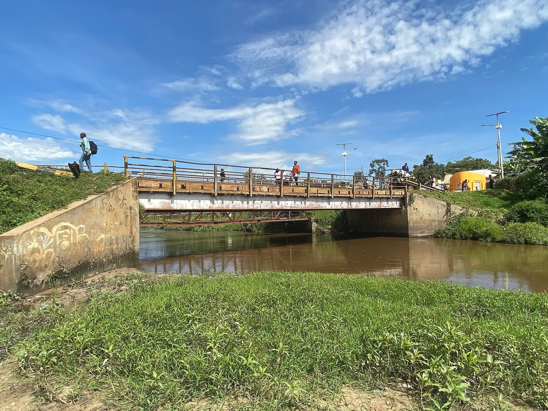 The River Rwizi at low water, its surface still and partly covered by floating vegetation